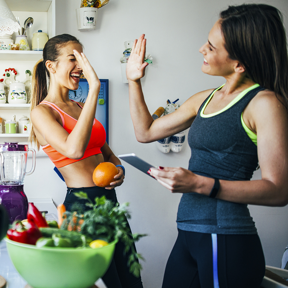 Zwei junge Frauen freuen sich über ein erfolgreiches Gesundheits-Coaching durch individuelle Ernährungsberatung